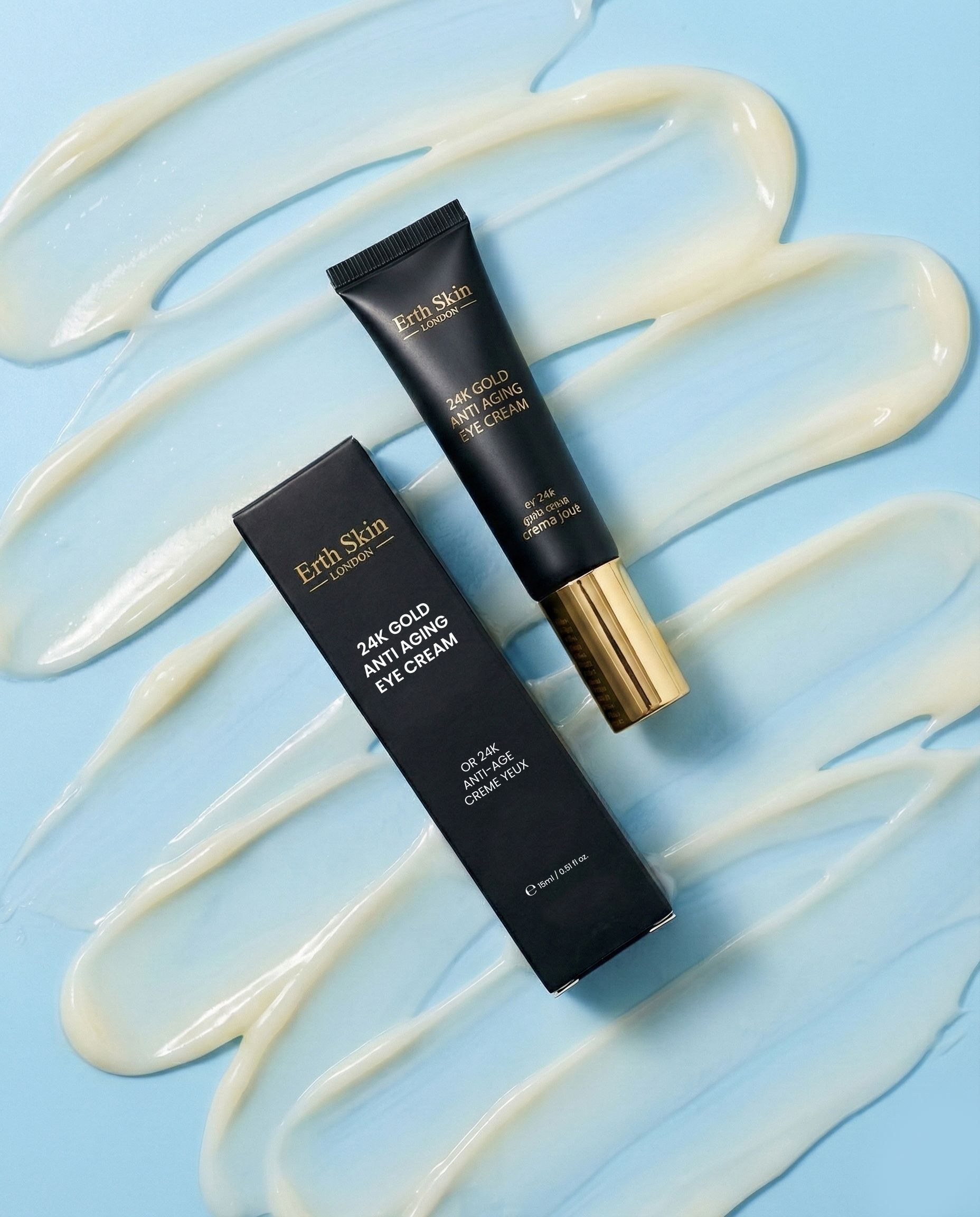 Tubo e scatola ErthSkin London Crema contorno occhi 24k Gold, circondati da strisce di crema.