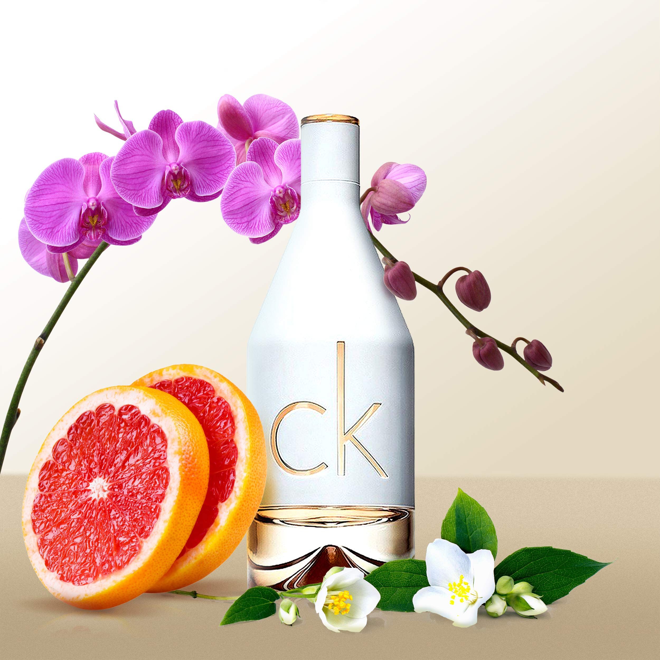 Flacone di profumo bianco con logo "ck" dorato. Decorato con pompelmo, orchidee e fiori di gelsomino.
