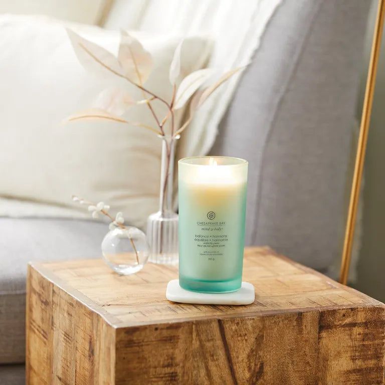 Candela verde su un tavolo. Scritta: Chesapeake Bay mind & body, balance + harmony, pera d'acqua. Candela accesa.