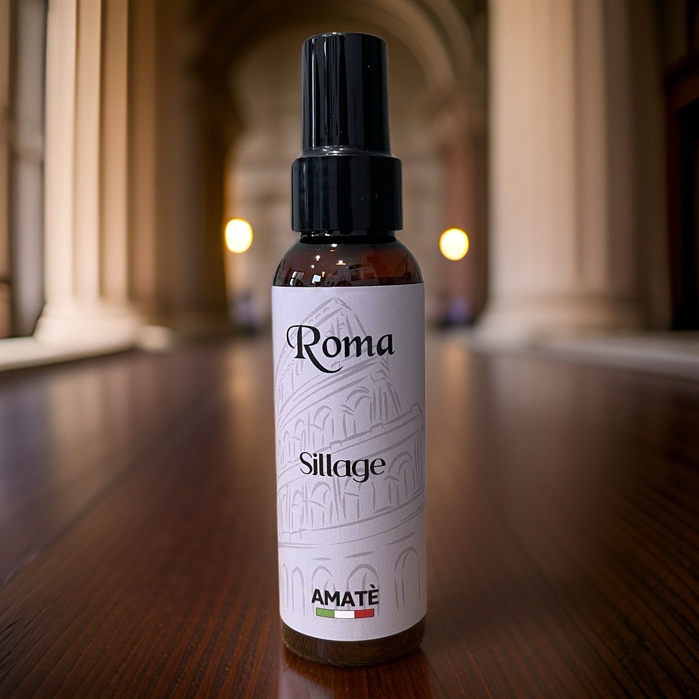 Flacone marrone con vaporizzatore nero su legno. Scritta "Roma Sillage" e "AMATÈ".