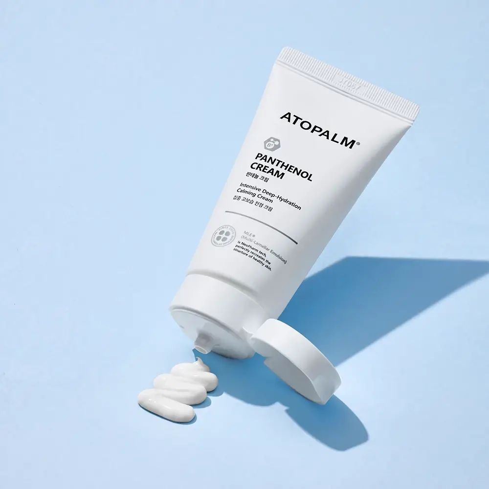 Tubo bianco con logo e nome del prodotto, con tappo aperto e prodotto. Scritta: ATOPALM, Panthenol Cream.