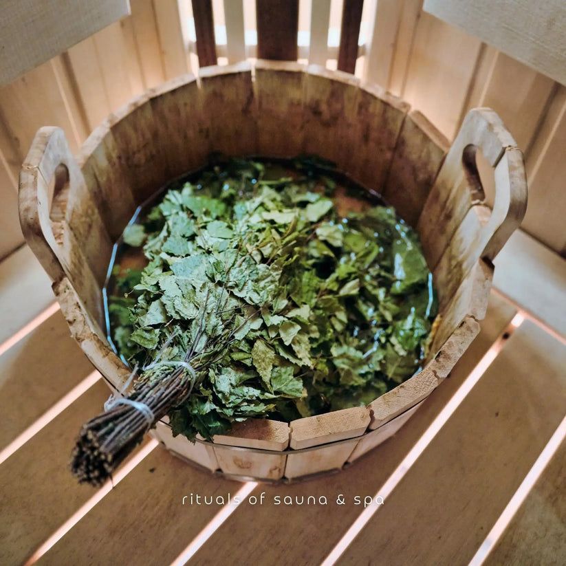 Fascio di betulla in un secchio di legno con acqua. Testo: Rituals of sauna & spa.