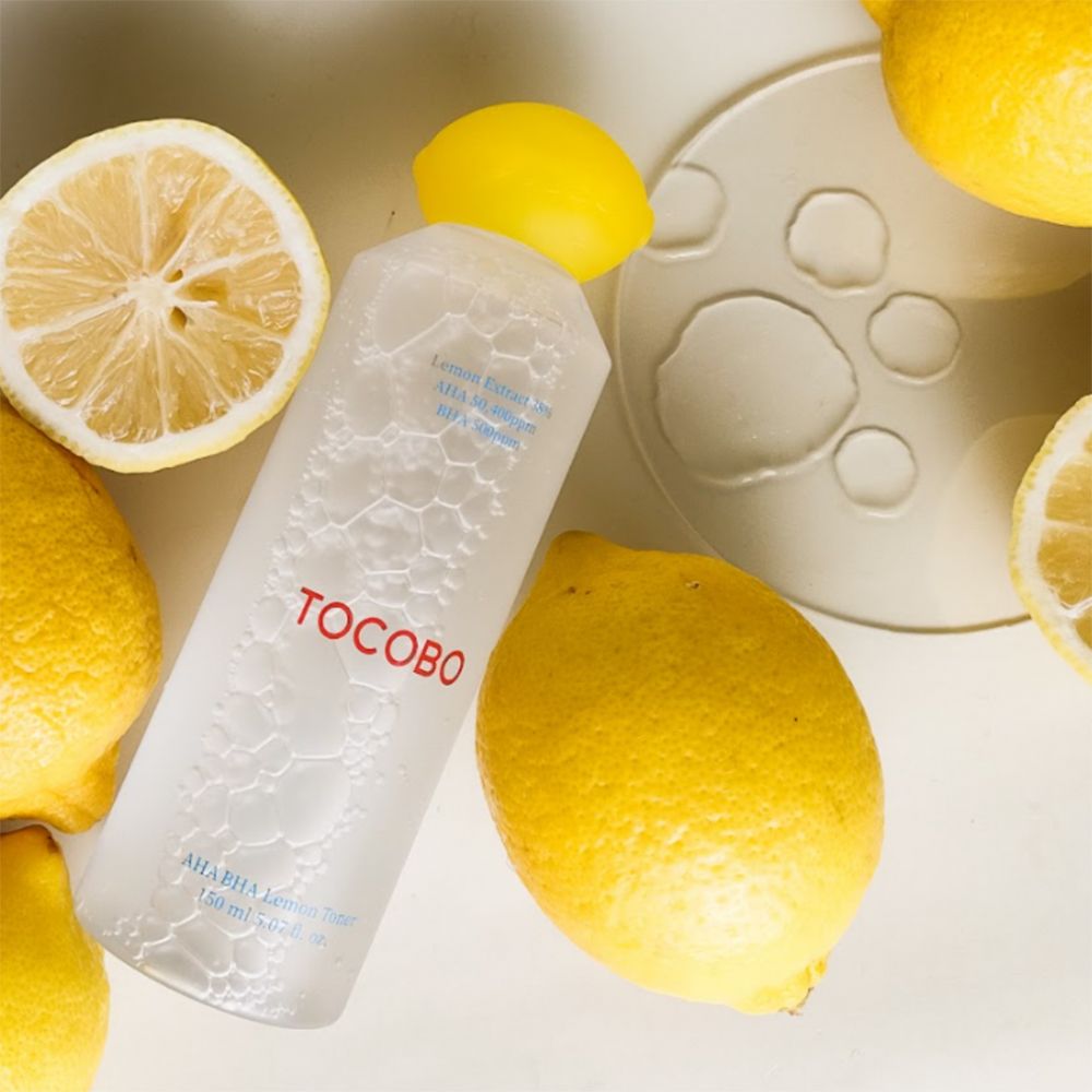 Flacone di toner al limone con limoni e piastra di vetro. Scritta TOCOBO. Testo: AHA BHA Lemon Toner, 150 ml.
