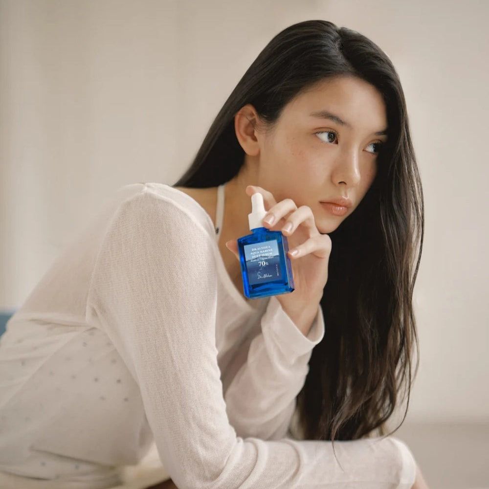 Donna che tiene in mano un flacone di siero blu. Scritta: Dr. Althea Aqua Marine Deep Serum, 70%.