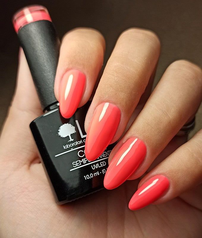 Mano con unghie smaltate arancioni. Accanto, un flacone di smalto. Scritta: LCI, Colore Semipermanente, UVLED 10,0 ml.