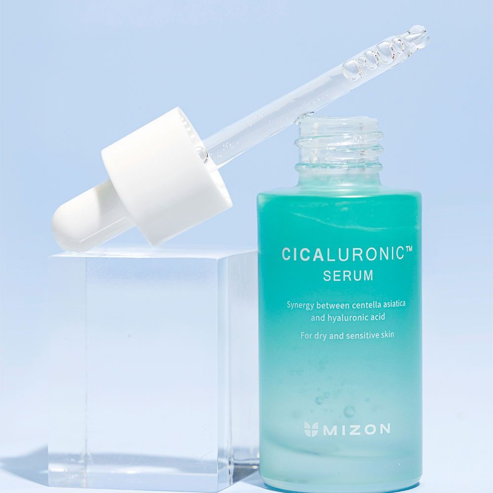 Flacone di siero verde con pipetta su un blocco trasparente. Scritta: Cicaluronic Serum. Marchio: Mizon.