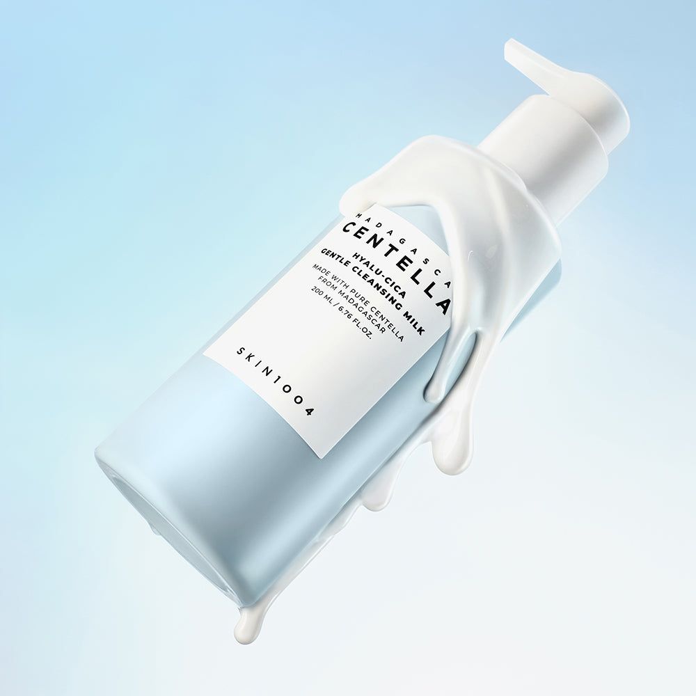 Flacone azzurro chiaro con erogatore bianco, circondato da crema. Etichetta con testo: MADAGASCAR CENTELLA HYALU-CICA. SKIN1004.