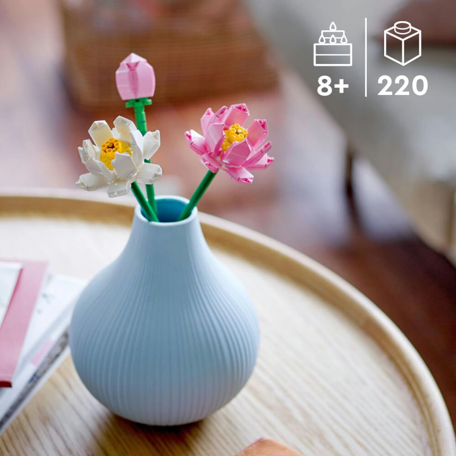 Tre fiori di loto in un vaso blu. Un bocciolo, due fiori aperti. Su un tavolo. Soggiorno sullo sfondo.