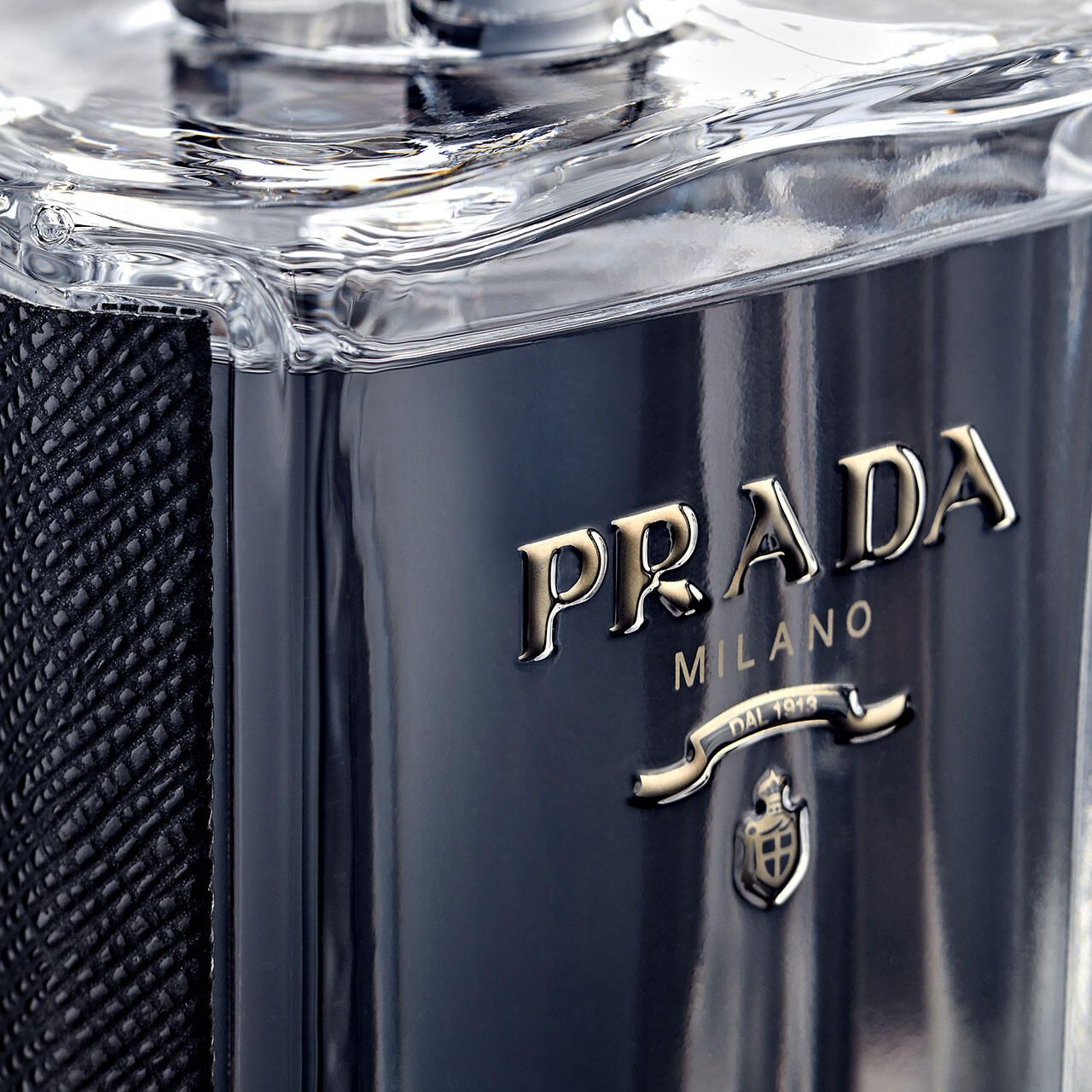 Primo piano del logo Prada su un flacone. Scritta dorata Prada Milano. Piccolo stemma sottostante.