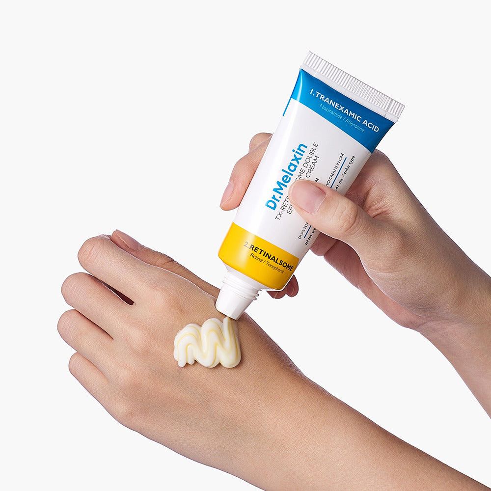Una mano preme un tubetto di crema contorno occhi doppia, una crema bianca e una gialla vengono applicate sull'altra mano.