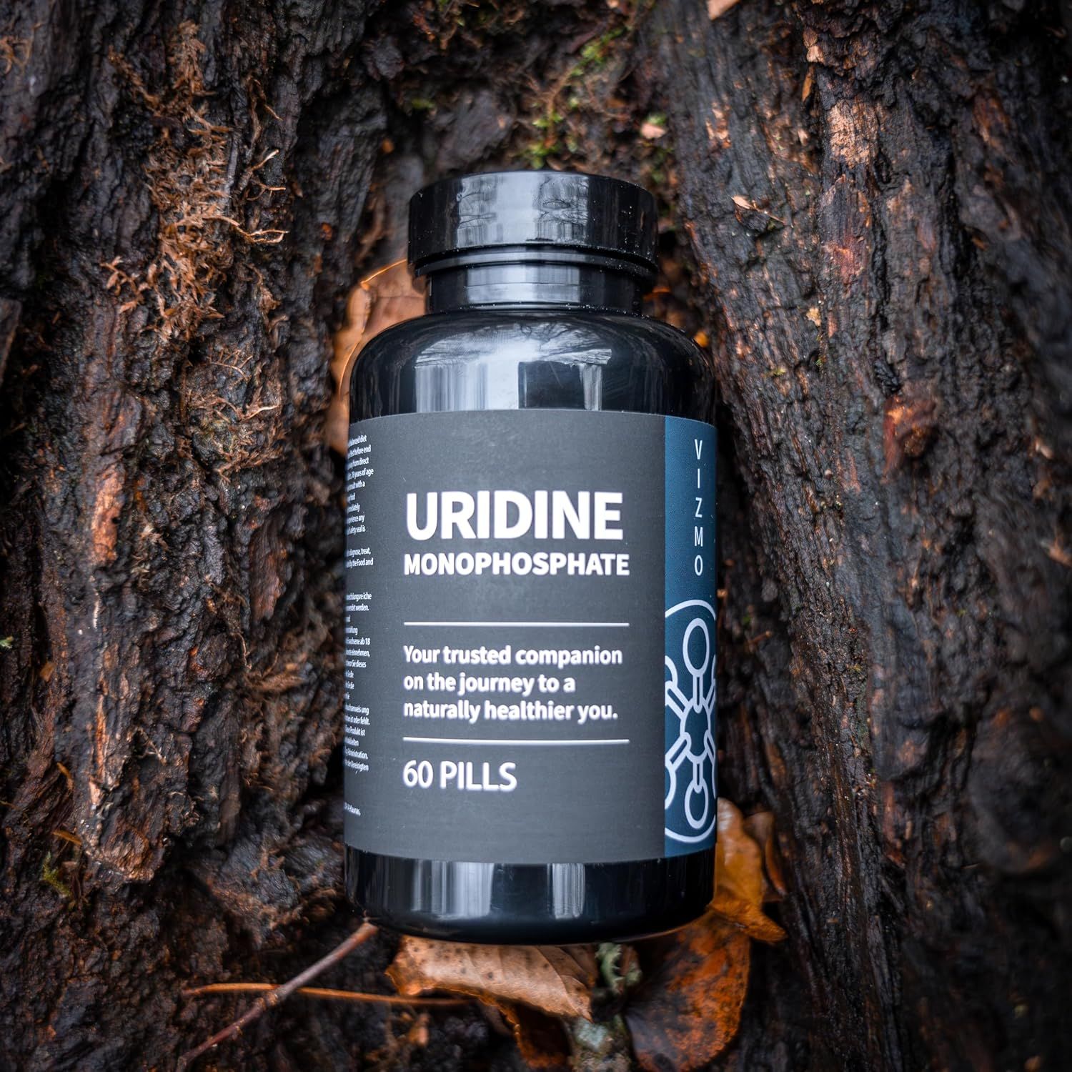 Flacone nero di capsule su un ceppo d'albero. Scritta: Uridina monofosfato, 60 pillole.