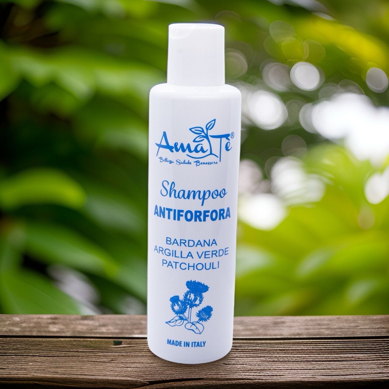 Flacone bianco con etichetta blu. Testo: Shampoo Antiforfora, ingredienti. Su superficie in legno.