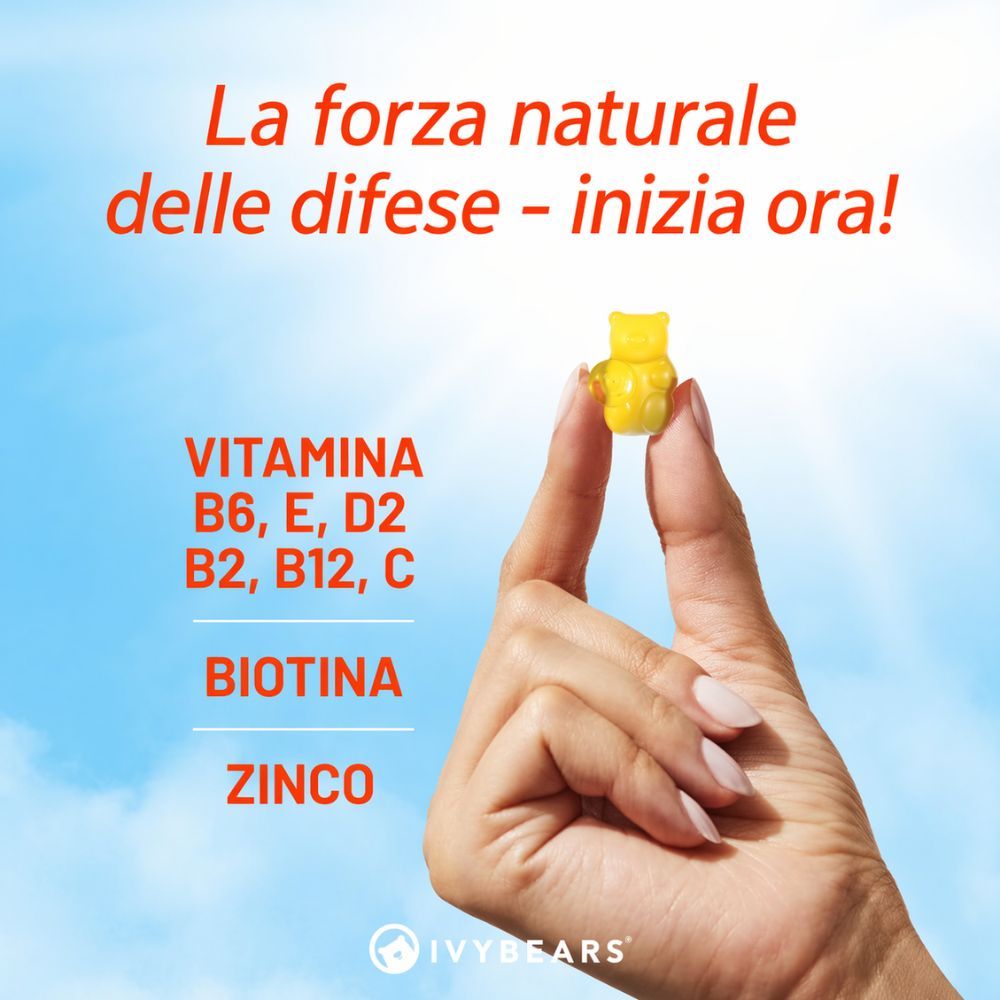 Mano che tiene un orsetto gommoso giallo. Testo: Vitamine B6, E, D2, B2, B12, C, biotina, zinco.