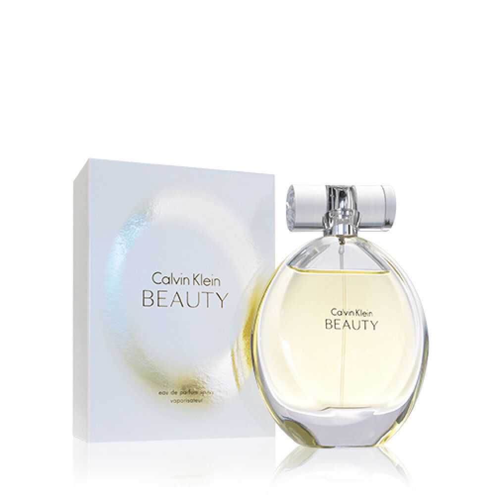 Flacone di profumo e confezione. Flacone rotondo, tappo argentato, liquido giallognolo. Confezione bianca, scritta Calvin Klein BEAUTY.