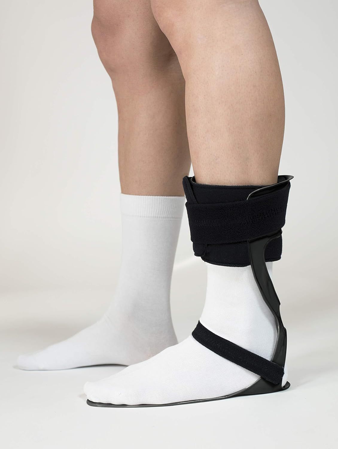 Tutore nero per caviglia con chiusure in velcro, indossato su calzino bianco.