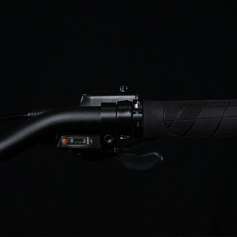 Manubrio di una bicicletta. Leva del cambio con numeri 1-6. Manopole nere.