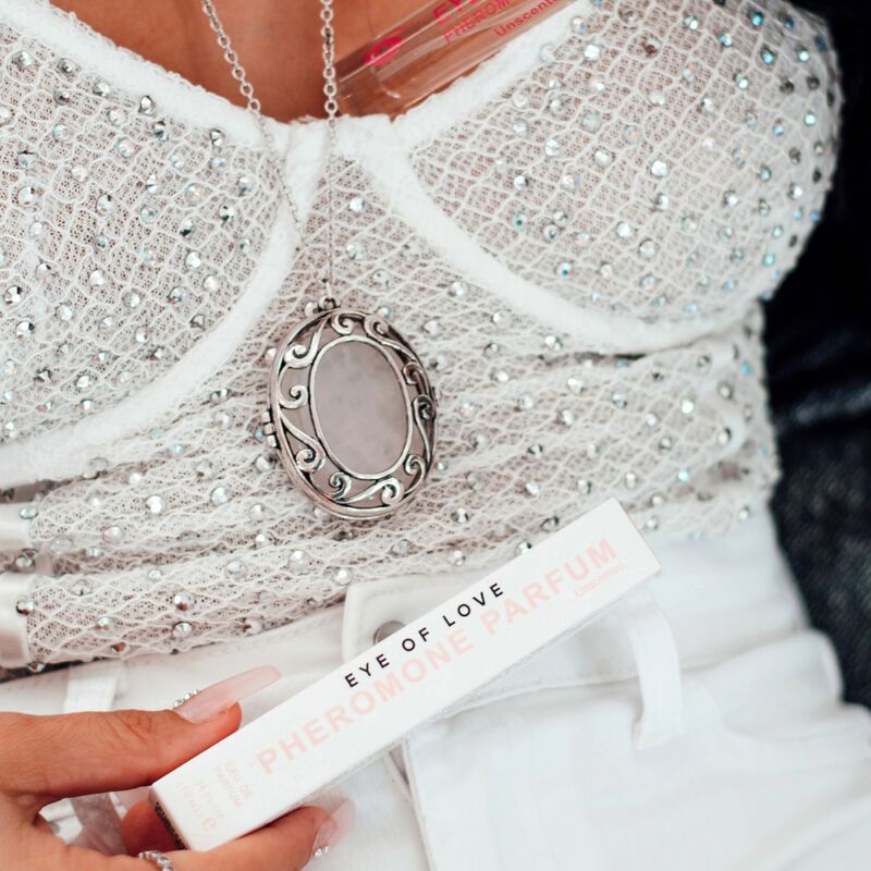 Confezione e flacone. Scritta: EYE OF LOVE PHEROMONE PARFUM. Donna indossa un top con gioielli.