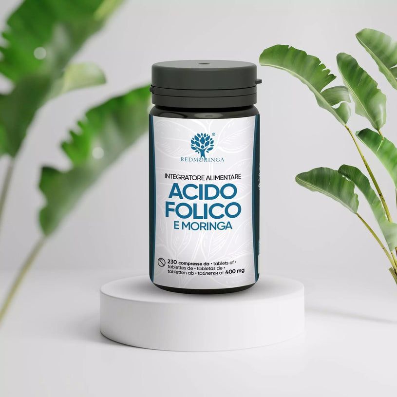 Flacone di Acido Folico e Moringa su piedistallo. Foglie verdi sullo sfondo.