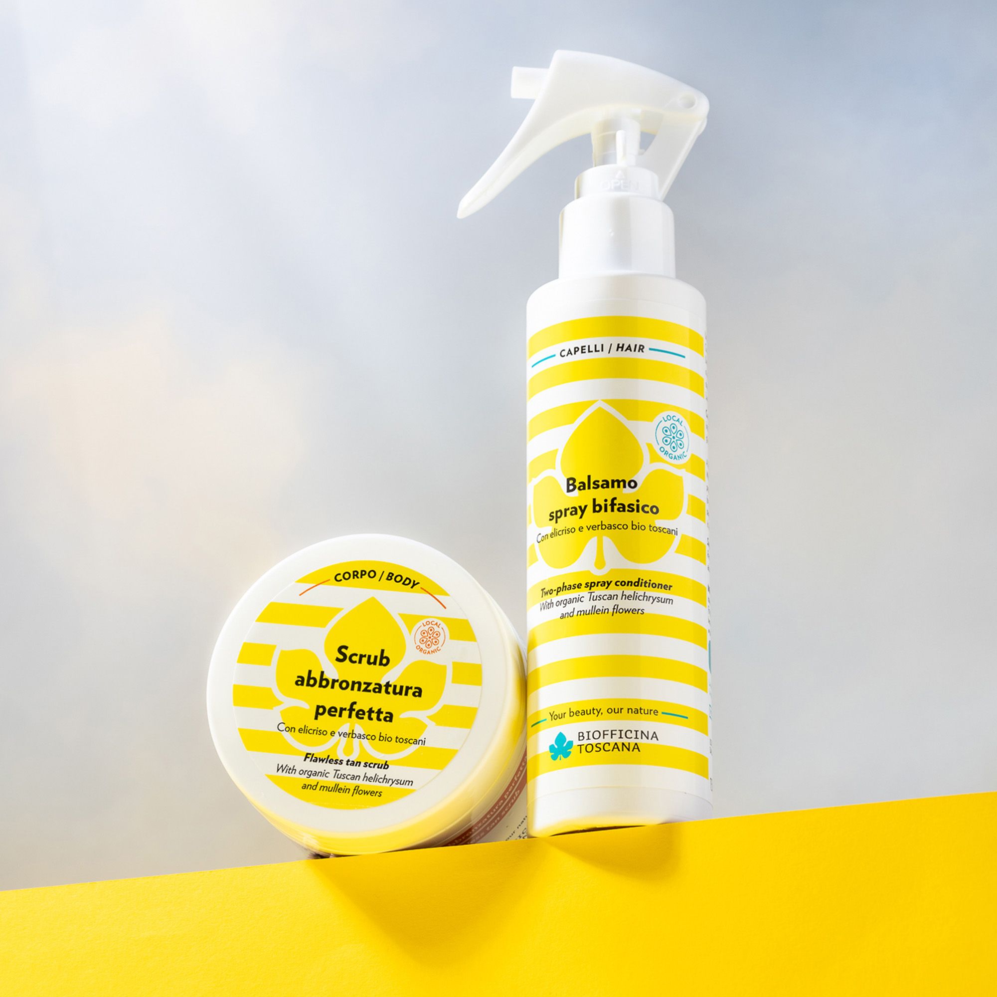 Due prodotti su sfondo giallo. Flacone spray e vasetto. Scritte: Balsamo spray bifasico e Scrub abbronzatura perfetta.
