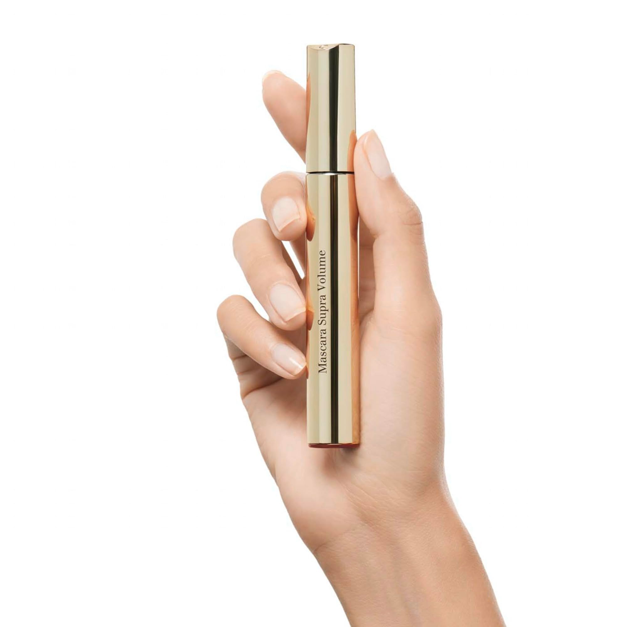 Tubetto mascara dorato in mano. Scritta: Mascara Supra Volume.