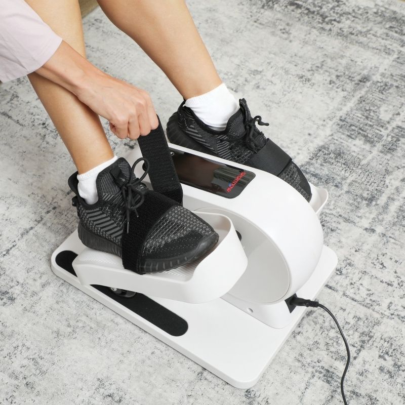 Primo piano: piedi in scarpe nere su mini ellittica. Cinghie nere. Persona che allaccia le cinghie.