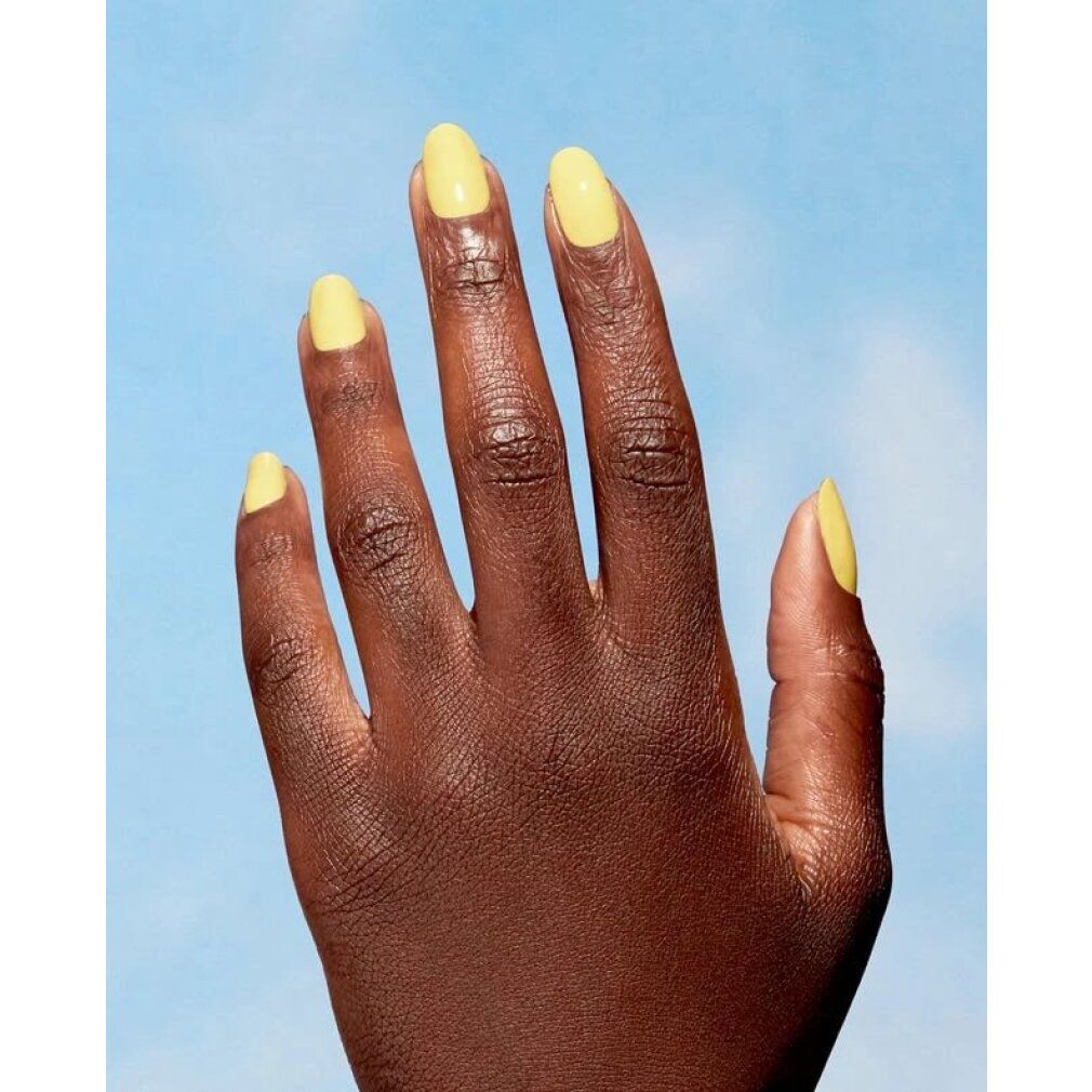 Una mano con smalto giallo, Make My Daisy di OPI Nature Strong. Le unghie sono dipinte con lo smalto giallo. Lo sfondo è blu.