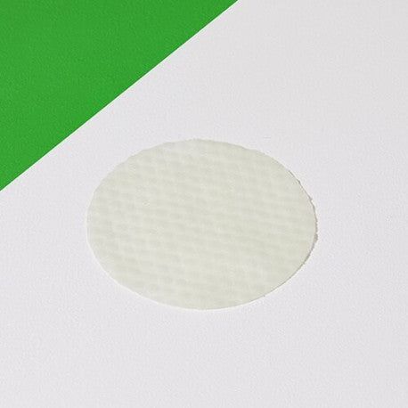 Tampone rotondo bianco su sfondo bianco con accento verde. Nessuna etichetta visibile.