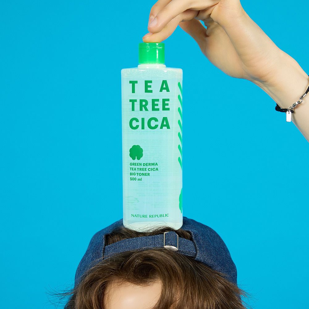 Flacone di toner sulla testa di una persona. Scritta: TEA TREE CICA. Marchio: NATURE REPUBLIC. Sfondo blu.