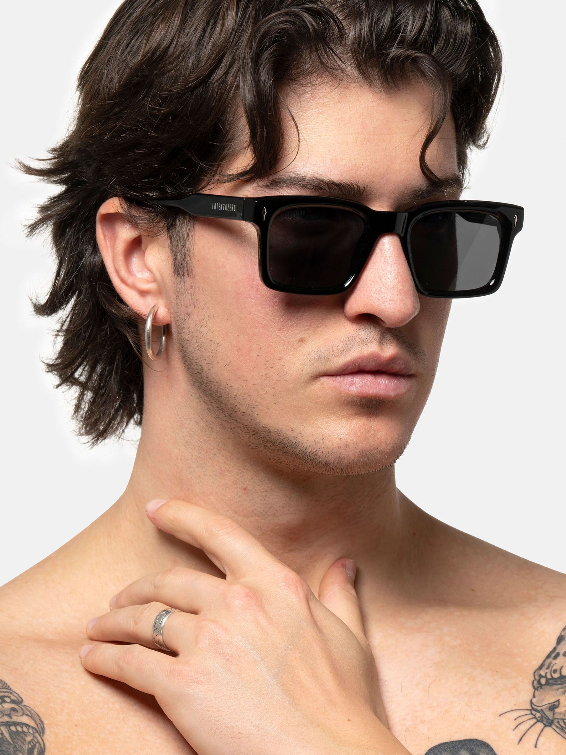 Uomo con occhiali da sole neri. Scritta LATENZAZERO sulla stanghetta.