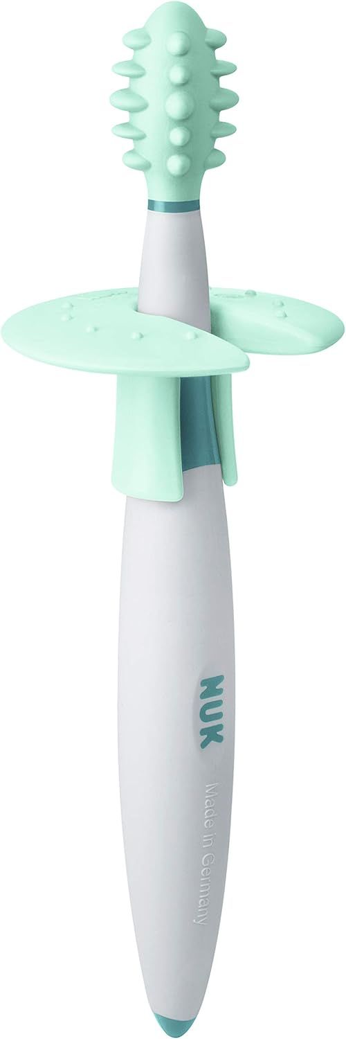 Spazzolino da allenamento con testina verde, manico bianco, parte centrale blu e anello protettivo. Logo NUK e Made in Germany.