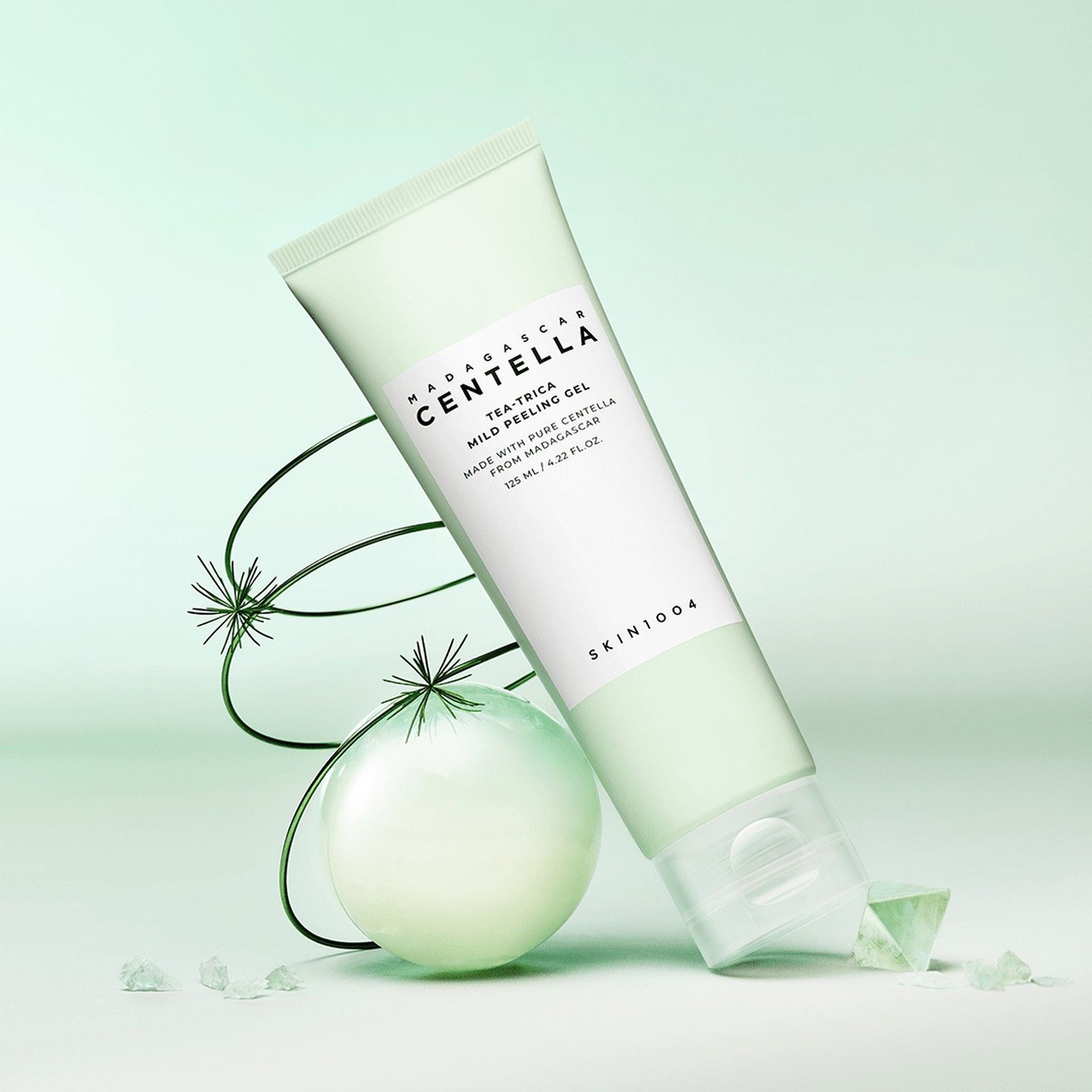 Tubo verde di gel esfoliante, circondato da elementi decorativi verdi.
