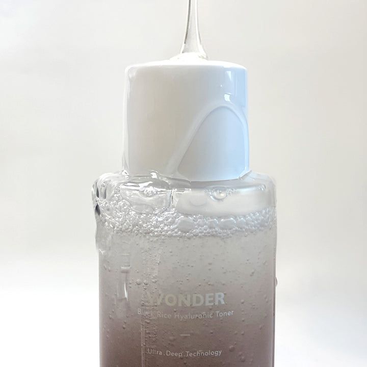 Primo piano di una bottiglia di toner da cui fuoriesce del liquido. Tappo bianco. Scritta: Haruharu wonder.