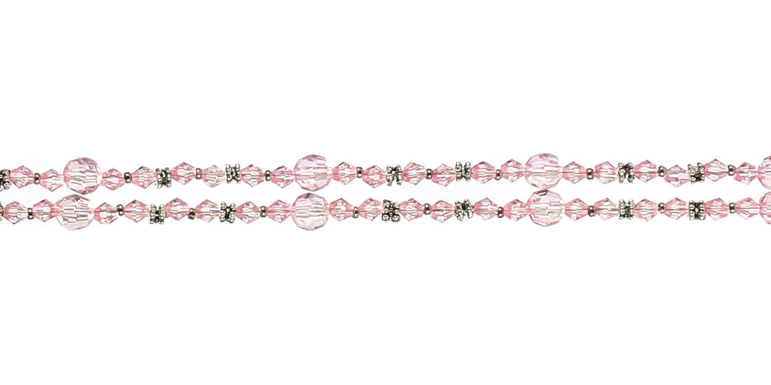 Primo piano di catenina per occhiali rosa con perline e dettagli metallici. Due fili paralleli.