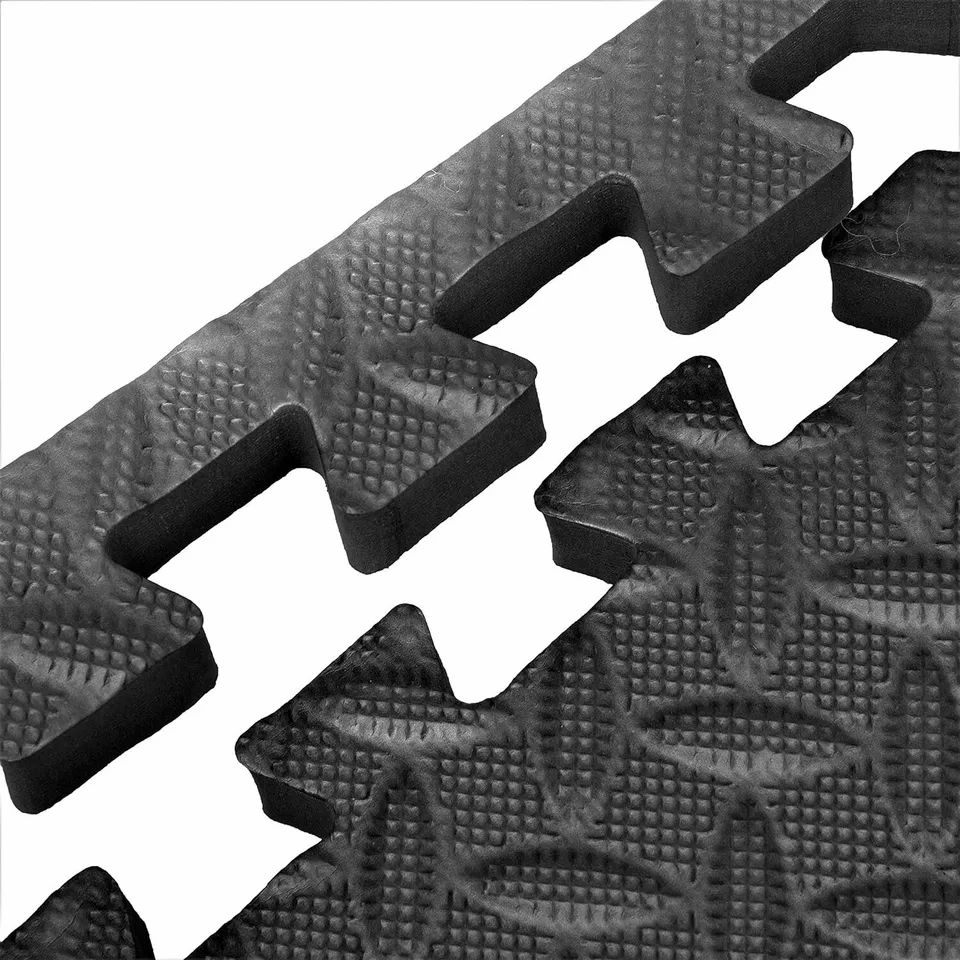 Primo piano di due tappeti puzzle neri. I tappeti hanno bordi ad incastro e superfici strutturate.