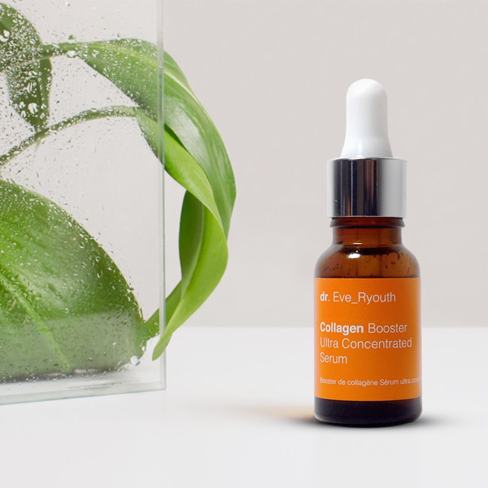Siero booster collagene Dr. Eve_Ryouth accanto a foglie verdi in un contenitore di vetro.