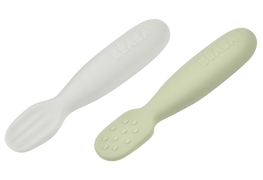 Due cucchiai per bambini. Uno bianco con punta scanalata, uno verde con borchie. Logo BEABA visibile.