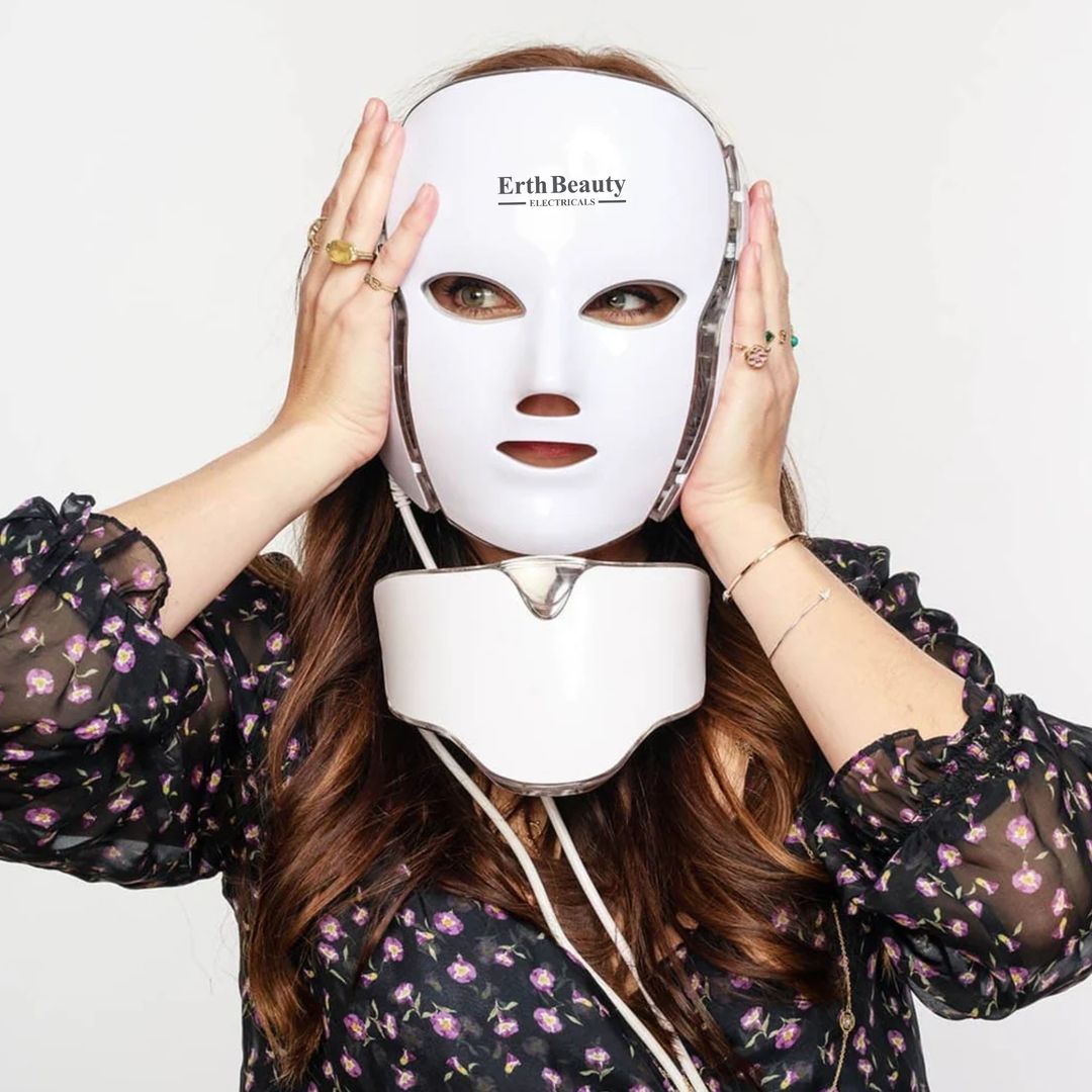 Una donna indossa una maschera facciale a LED bianca. La maschera riporta "Erth Beauty". Tocca la maschera con le mani.