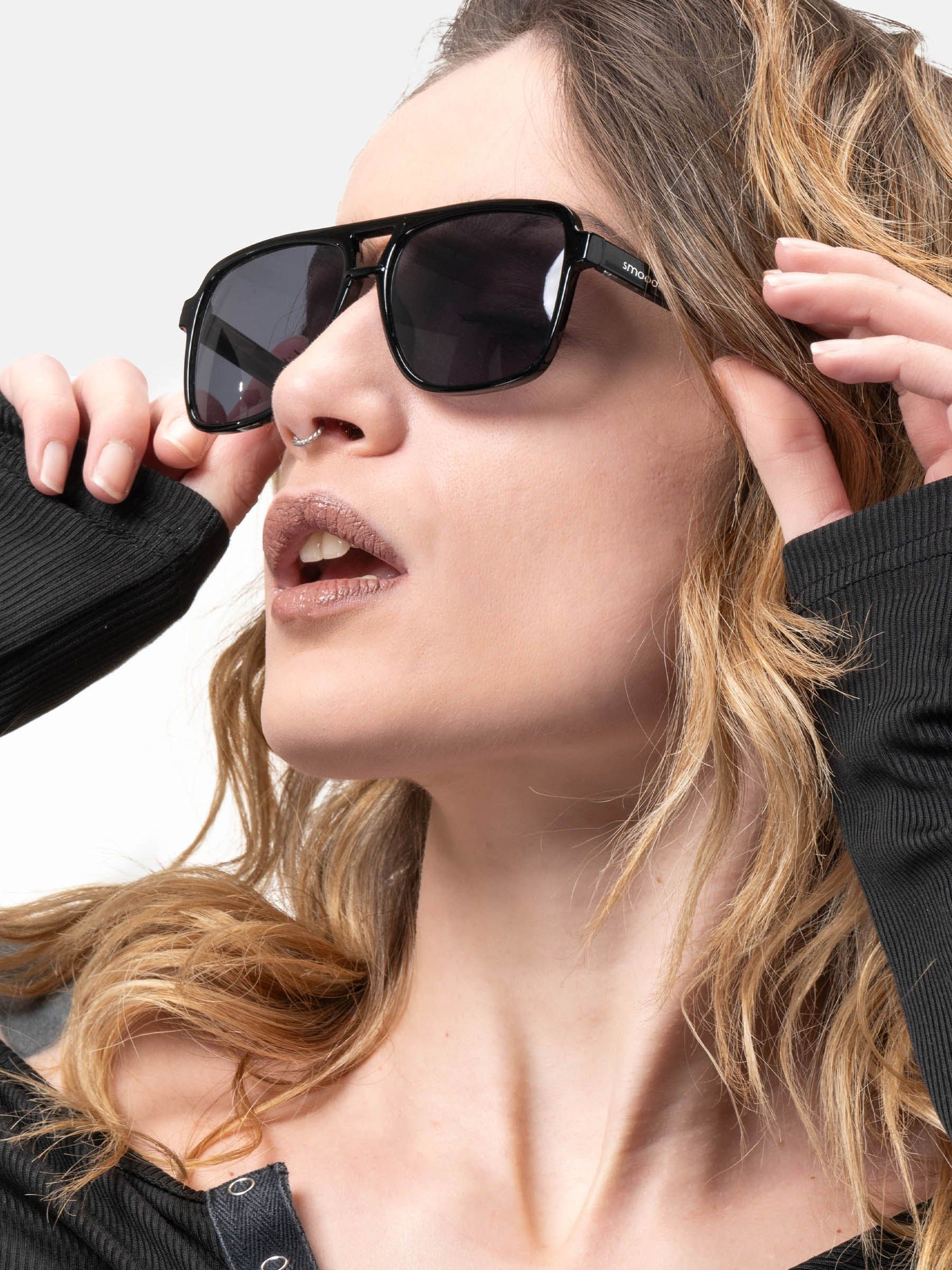 Persona indossa occhiali da sole neri. Logo "smooder" sull'asta visibile.