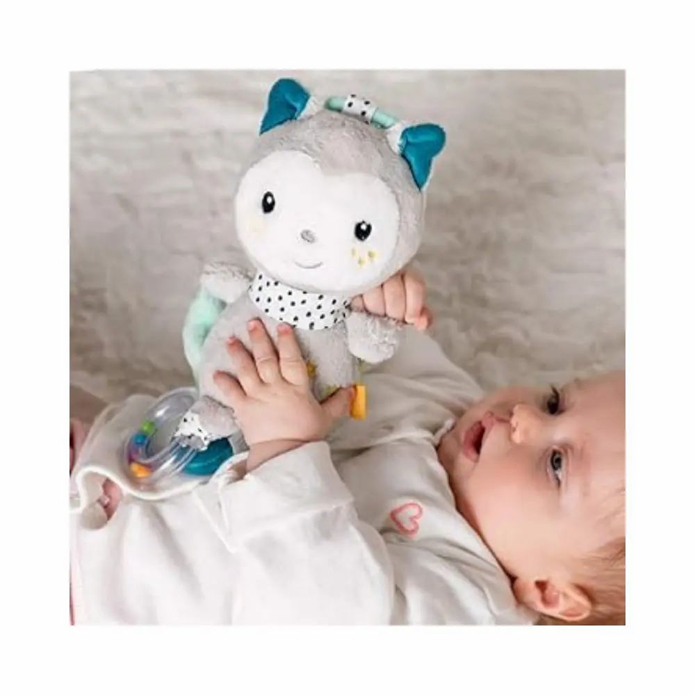 Bambino tiene in mano peluche grigio con orecchie blu e sciarpa a pois. Con stella, specchio e sonaglio. Su sfondo bianco.