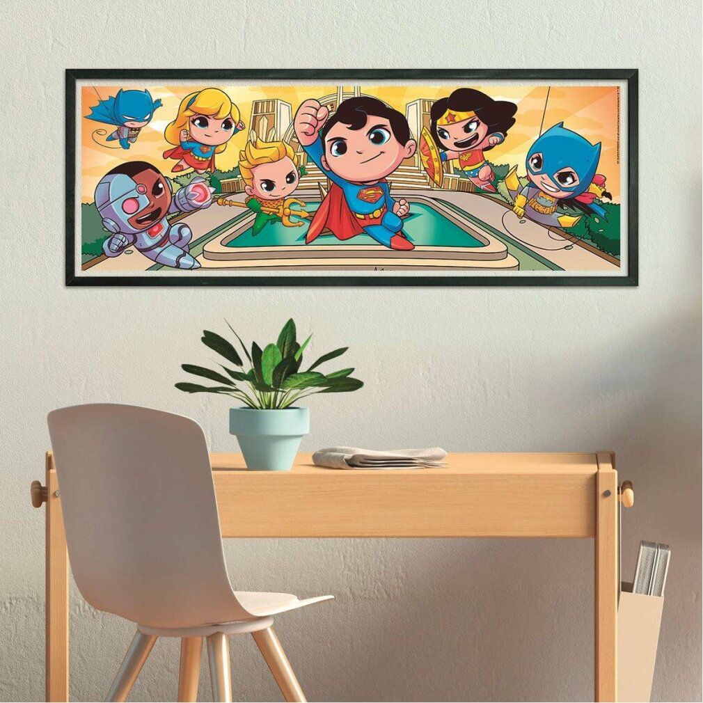 Puzzle finito con motivo DC Super Friends. Superman, Wonder Woman, Batman e altri personaggi. Posizionato su una scrivania. Cornice.