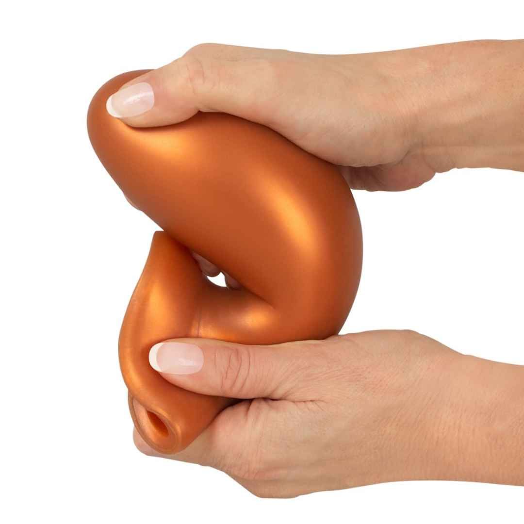 Plug anale arancione con ventosa, compresso tra le mani.