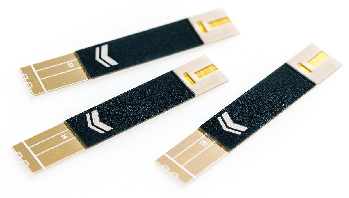 Tre strisce reattive per la misurazione della glicemia. Striscia nera con frecce bianche ed estremità dorate. Nome prodotto: CodeFree.