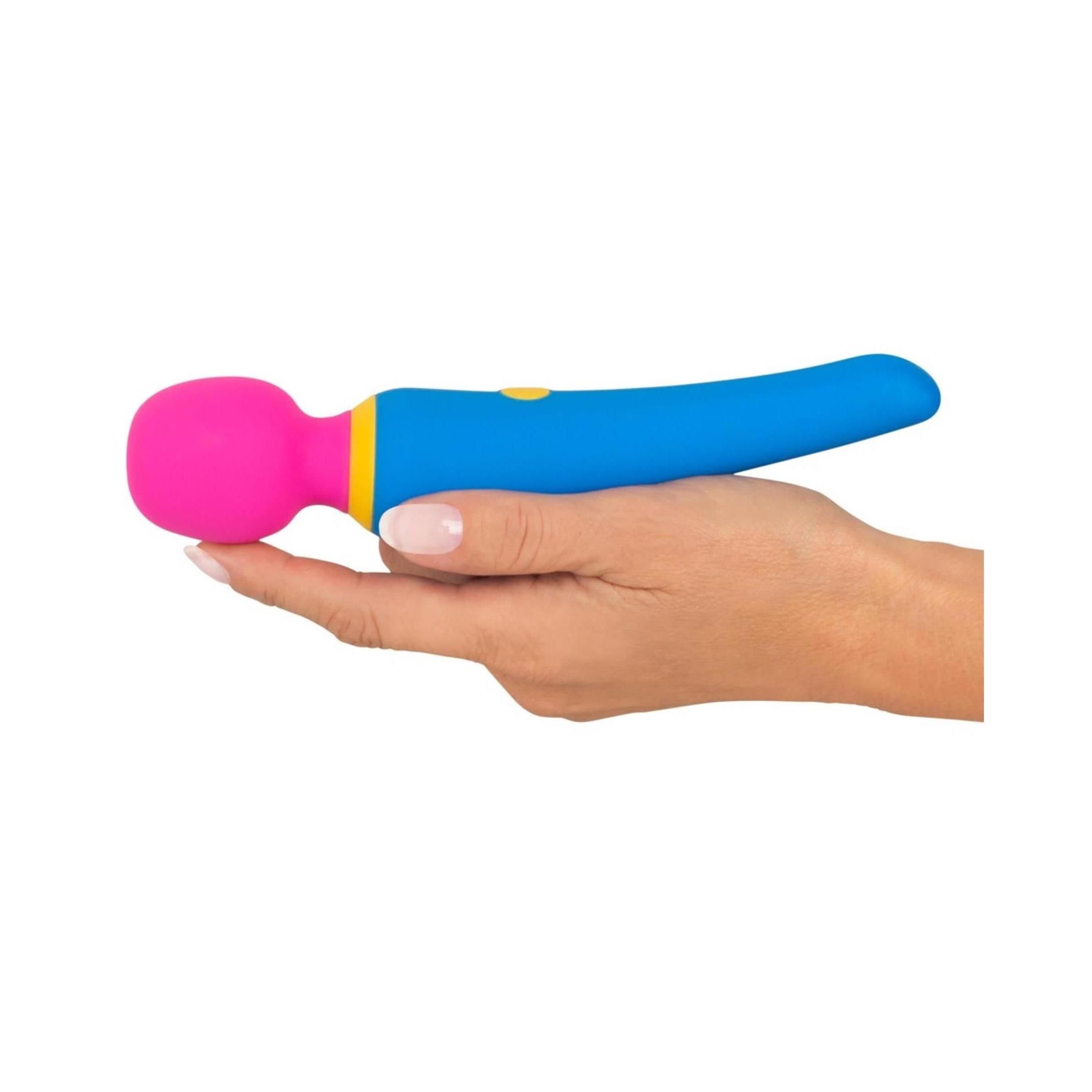 Mano che tiene un vibratore blu, giallo e rosa. Impugnatura cilindrica, testa rotonda. Bottone giallo.