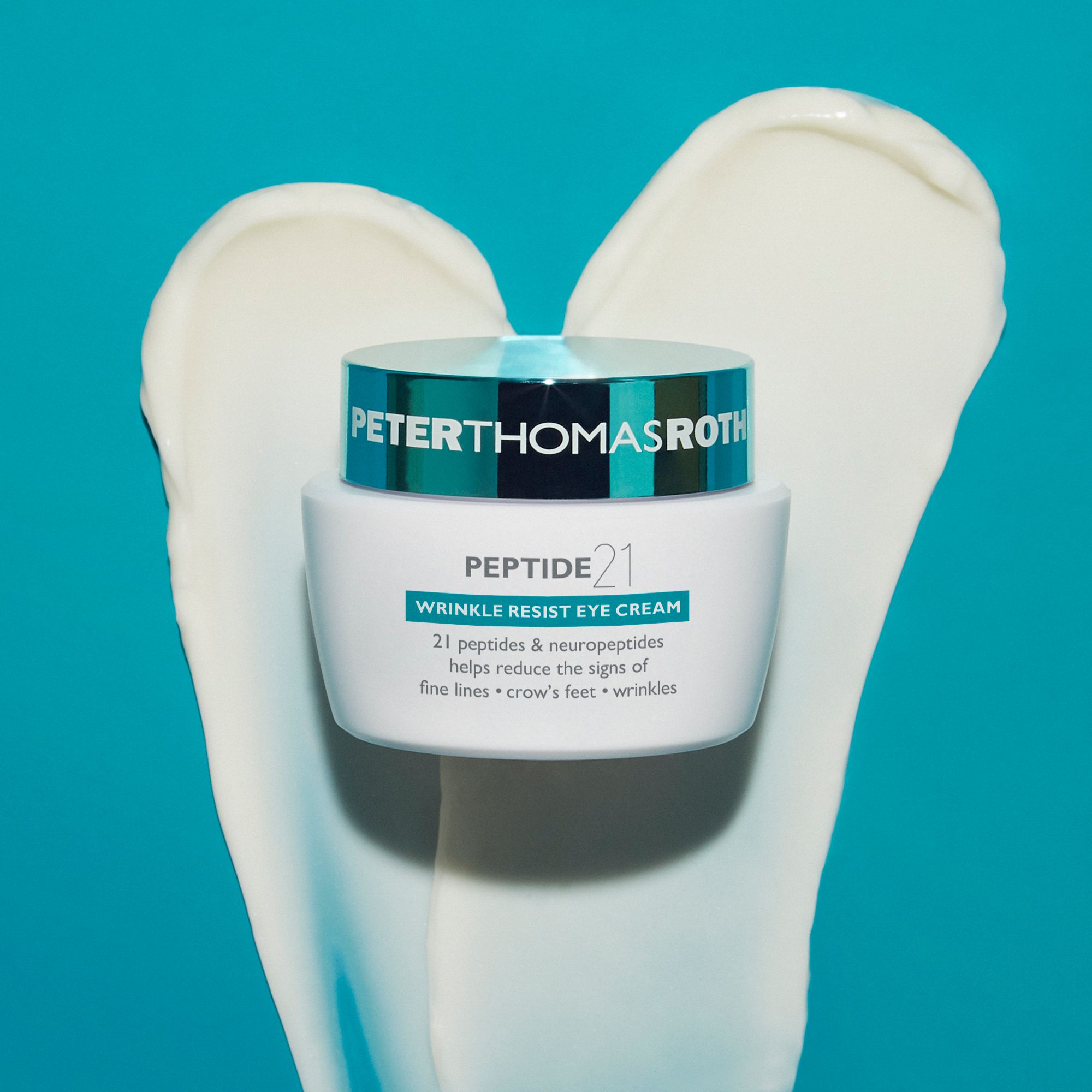 Peter Thomas Roth Peptide 21® Wrinkle Resist Eye Cream. Vasetto su macchia di crema. Sfondo blu.