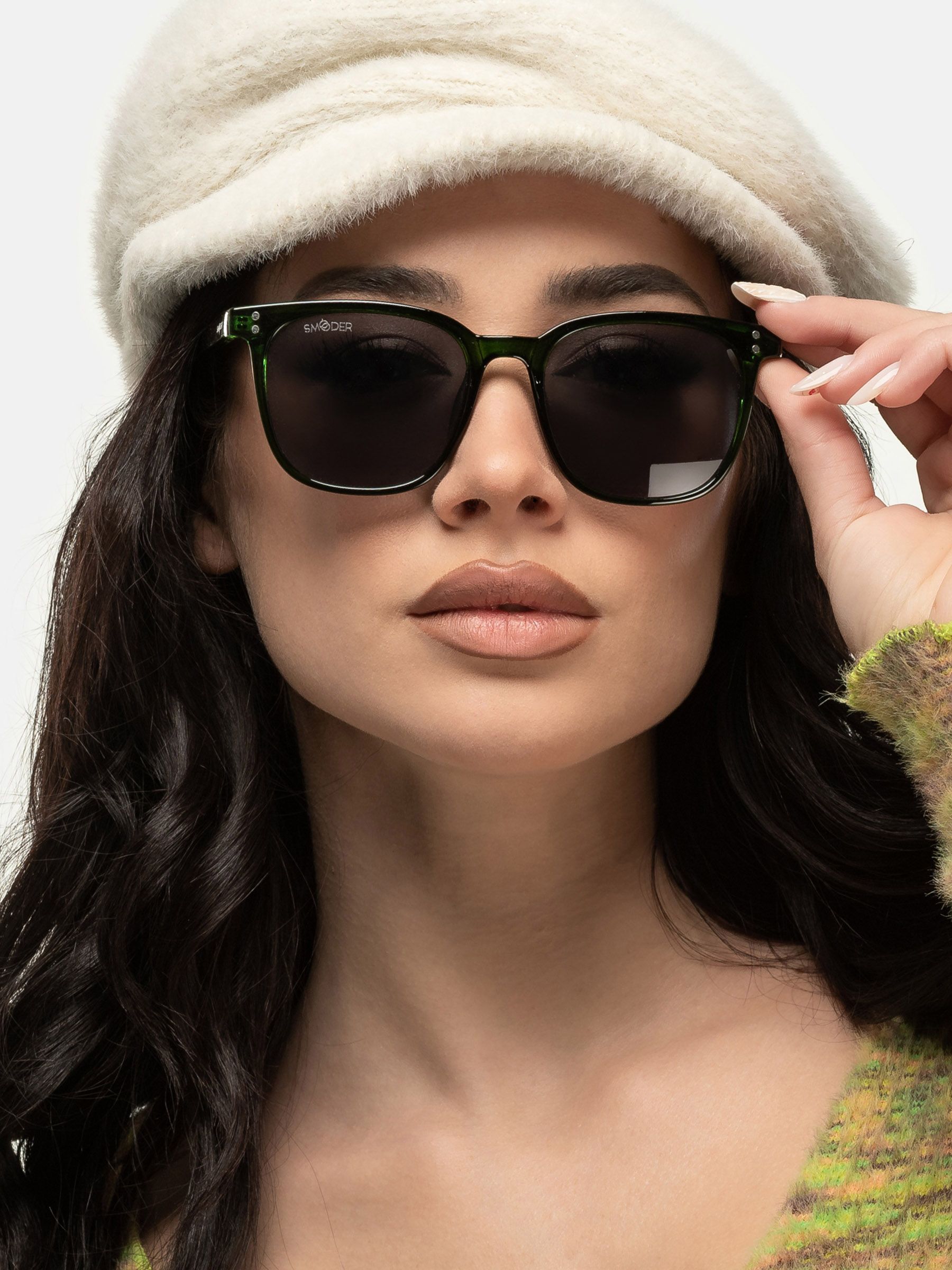 Persona indossa occhiali da sole verdi. Forma rettangolare, lenti scure. Marchio Smooder sull'asta. Con cappello.
