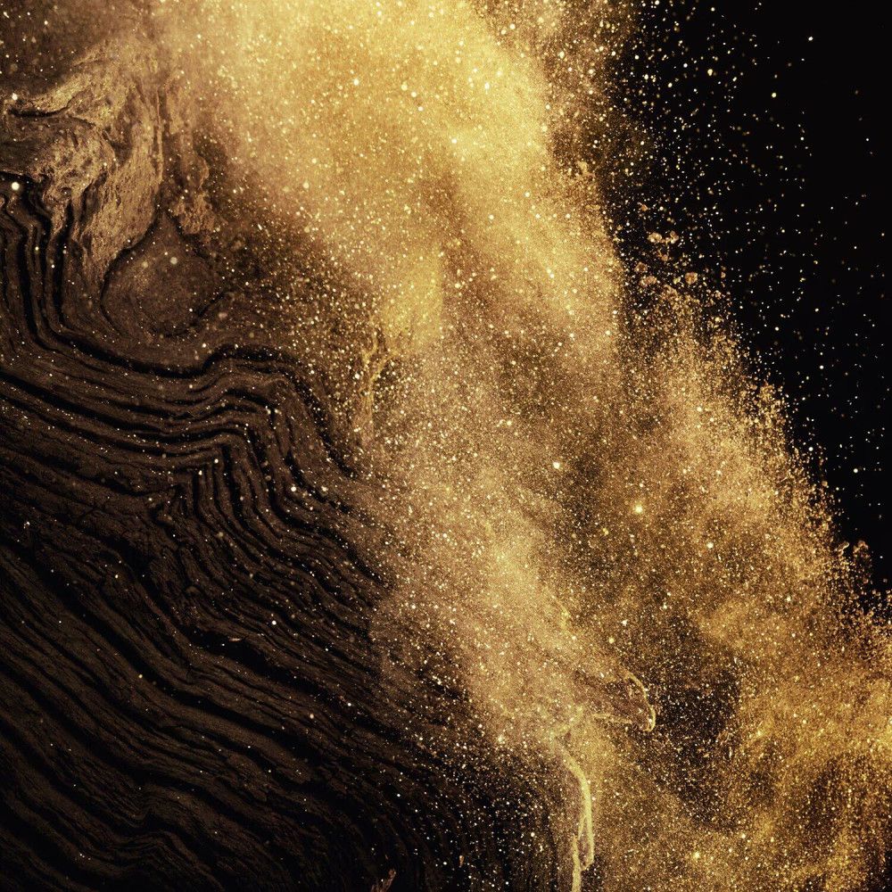 Rappresentazione astratta di polvere d'oro e superfici scure e strutturate. Particelle chiare su sfondo scuro.