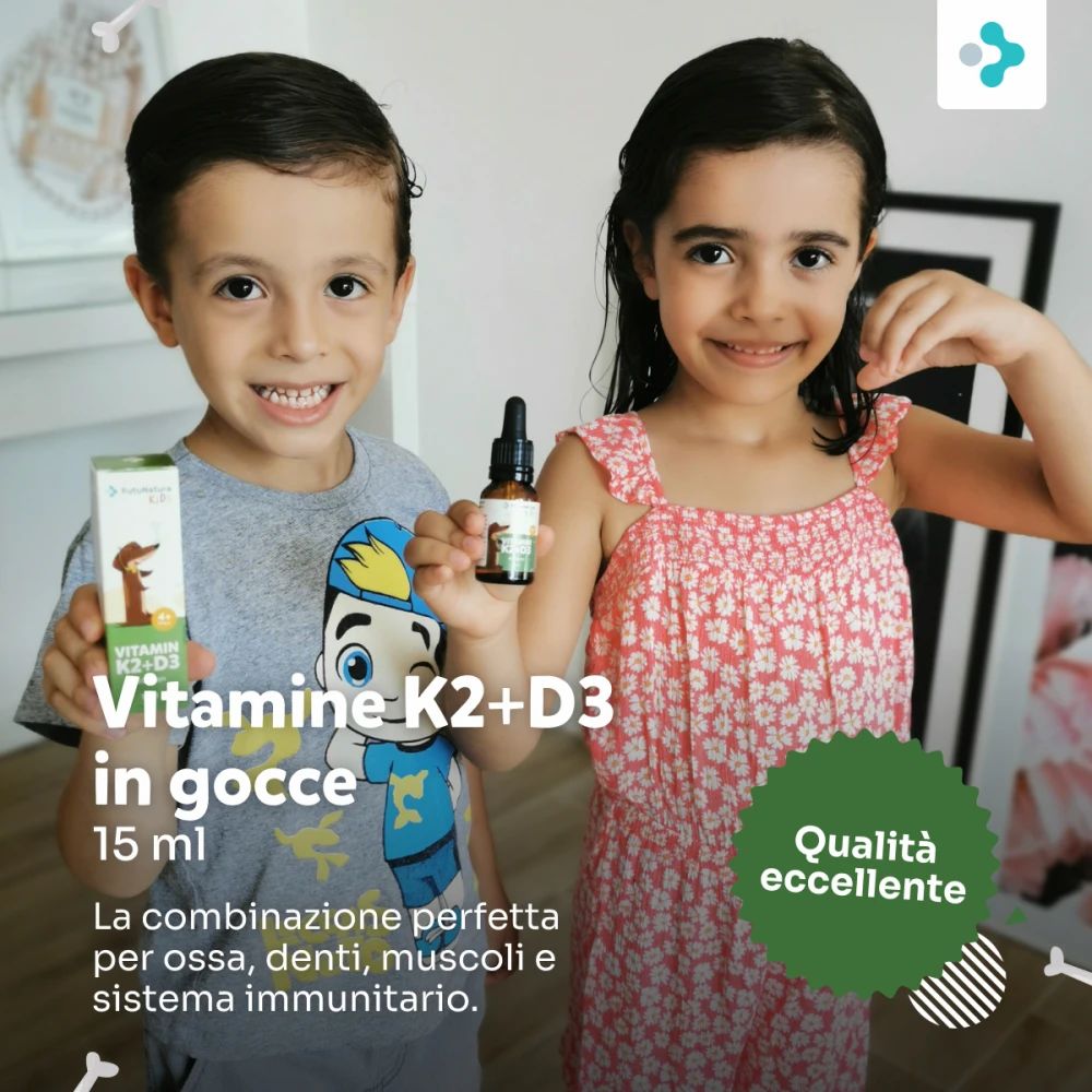 Due bambini tengono in mano flacone e confezione. Scritta: Vitamine K2+D3 in gocce, 15 ml. Sulla confezione: cane.