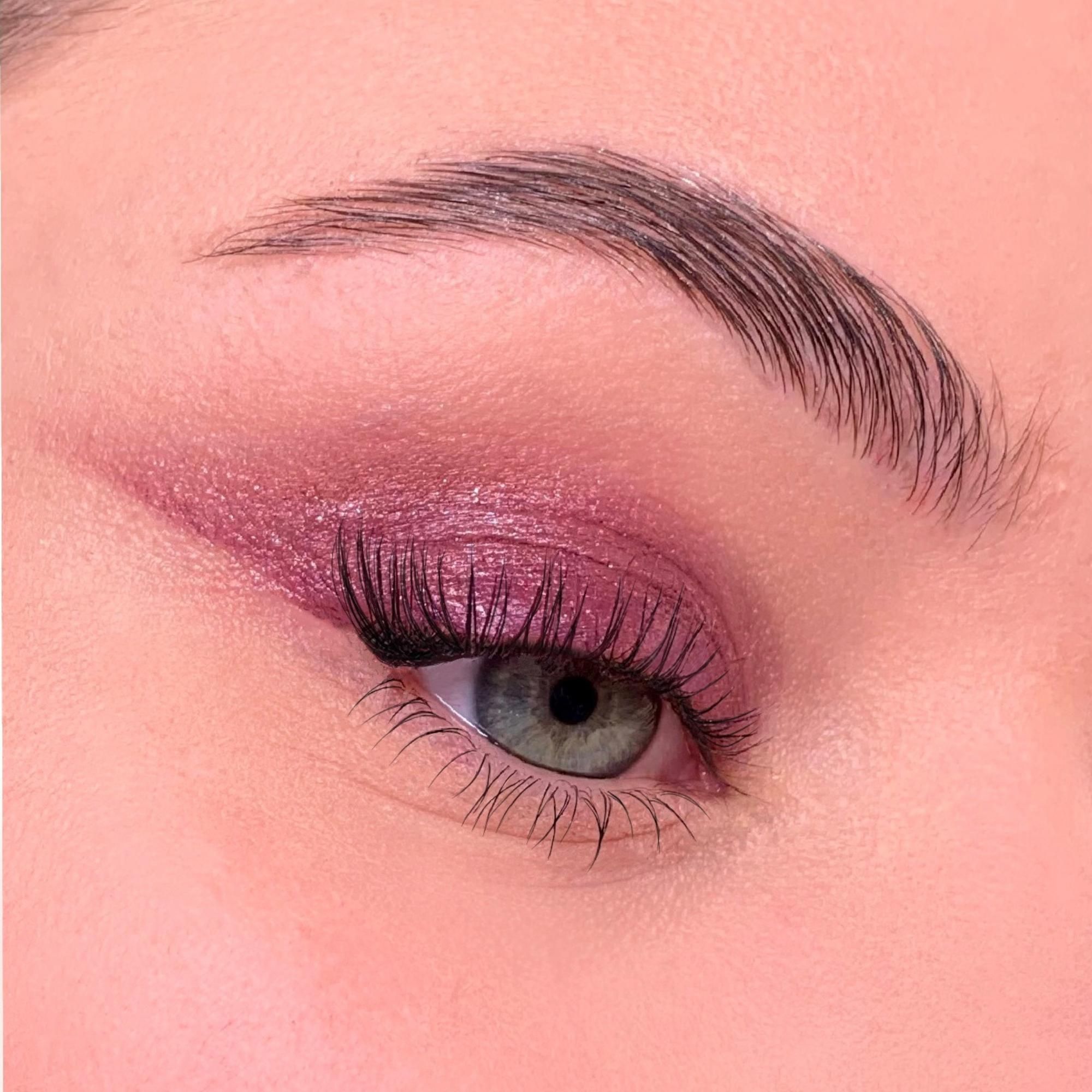 Primo piano di un occhio con ombretto. Palpebra evidenziata con ombretto rosa. Ciglia allungate.