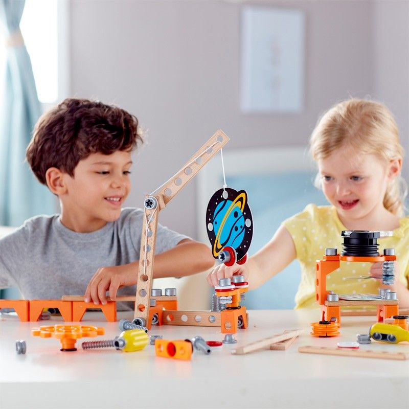 Due bambini giocano con un giocattolo da costruzione. Il giocattolo è in legno e plastica, con decorazione pianeta.