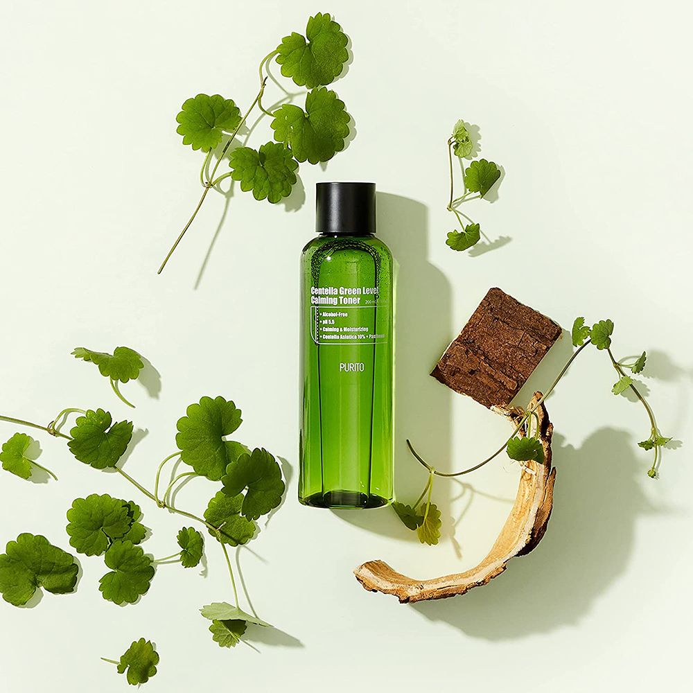 Flacone verde con tappo nero, circondato da foglie e legno. Scritta: Centella Green Level Calming Toner.